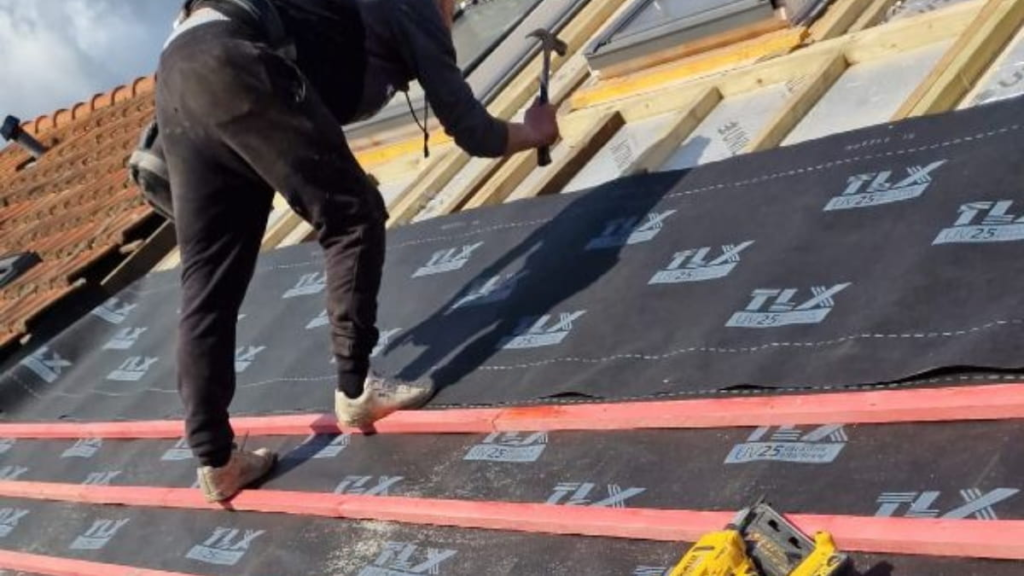 Roofer installing roofing membrane and timber battens.